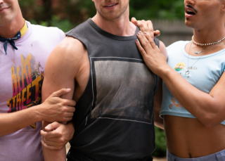 From left to right: Matt Rogers, Zane Phillips and Tomás Matos in the film Fire Island. Rogers and Matos are draping their hands affectionately on Phillips.
