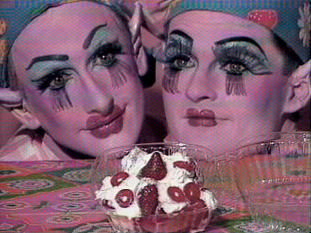 Two pink faces, painted like clowns with blue eyeshadow and caps, resting on a table and staring at a punnet of strawberries in cream, in a still taken from Tom Rubnitz's 1989 film strawberry shortcut